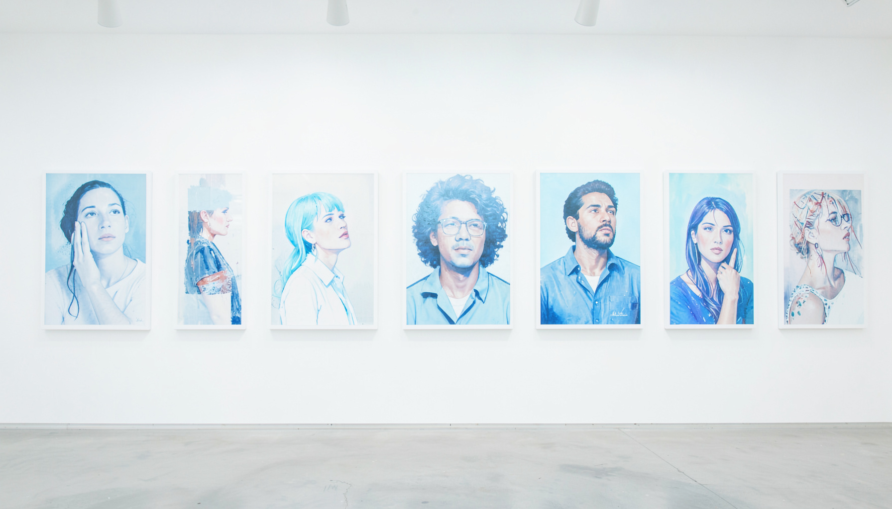 A gallery wall showing a row of contemporary self-portraits in varied styles, lit evenly from above